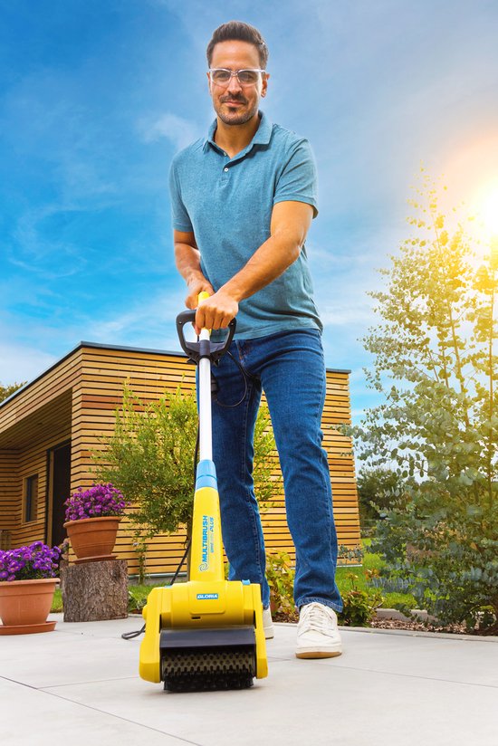 Man met veiligheidsbril gebruikt gele Gloria Multibrush op betegeld terras.