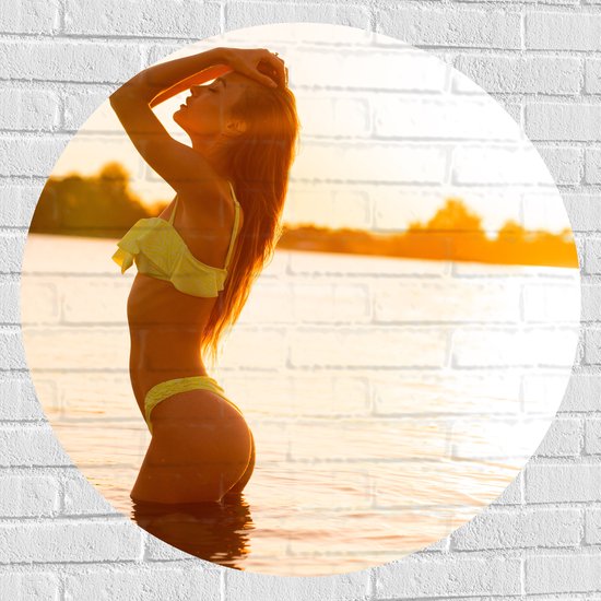 Muursticker Cirkel - Sierlijke Vrouw in Gele Bikini in het Water bij Zonsondergang - 90x90 cm Foto op Muursticker