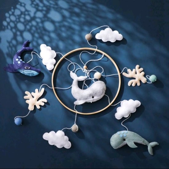 Houten ring met hangende vilten decoraties: grijze walvis, blauwe walvis, mintgroene walvis, wolken, koraal en ballen, op een donkerblauwe achtergrond.