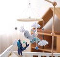 Houten babybed hanger met vilten decoraties: grijze walvis, blauwe walvis, mintgroene walvis, wolken, koraal en ballen, hangend boven een ledikant.