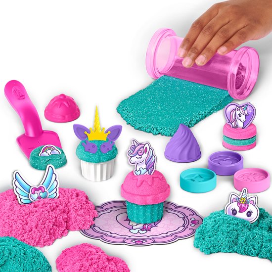 Glitterzand in roze en turquoise met vormpjes, stickers, lepels, een schepje en gemaakte cupcakes met unicorn-thema.