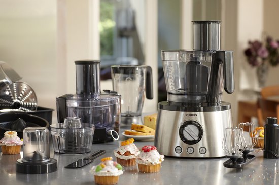 Een Philips keukenmachine met accessoires, cupcakes en cake in de keuken.