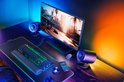 Gaming bureau met Razer speakers, toetsenbord, muis en monitor met groen/geel licht.