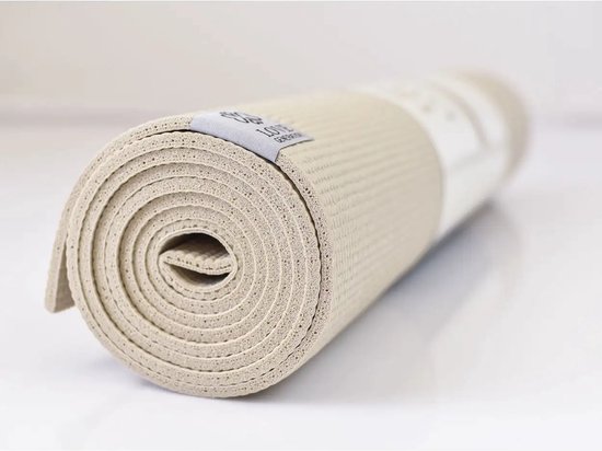 Close-up van een opgerolde beige yogamat met een licht gestructureerd oppervlak en een grijs label.