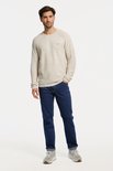 Man in een spijkerblauw denim spijkerbroek met bruine stiksels, recht model.