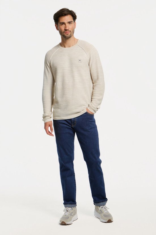 Man in een spijkerblauw denim spijkerbroek met bruine stiksels, recht model.
