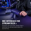 Een persoon gebruikt de Stream Deck+ als microfooninterface op een bureau, met een microfoon in de buurt.