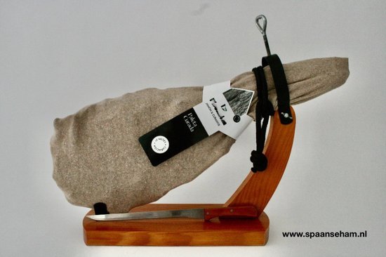 Een hele Paleta Curada ham in bruine hoes, met een mes op een houten standaard.