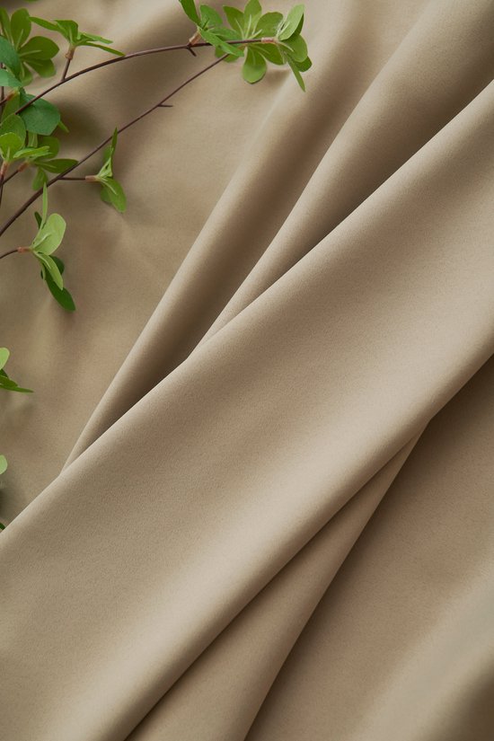Draperie van licht taupe stof met een zachte textuur, met groene takjes.