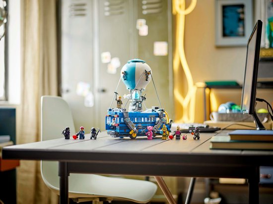 Bus de combat LEGO avec ballon et figurines sur un bureau.