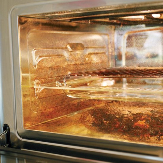 Binnenkant van een oven met vetresten en aangekoekte aangekoekte etensresten op de wanden en de grill.