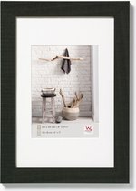 Zwarte houten fotolijst met een wit passe-partout, getoond met een natuurlijke decoratie.