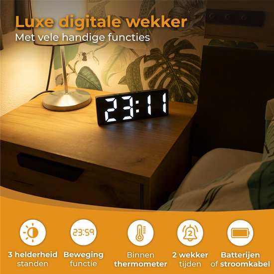Zwarte digitale wekker op een nachtkastje toont 23:11. Naast het bed staat een lamp. Iconen: 3 helderheid standen, beweging, thermometer, 2 wekkers, batterijen.