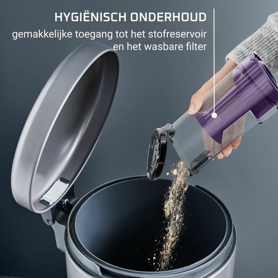 Een hand ledigt de paarse stofcontainer van een kruimeldief in een grijze vuilnisbak.