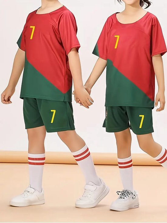 Twee kinderen in een rood-groen voetbaltenue met nummer 7 op de voorkant, witte sokken met rode strepen.
