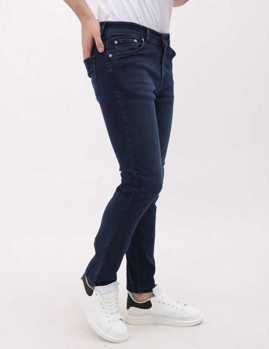 Blauwe stretch jeans met regular fit voor heren. Gedragen met witte sneakers.