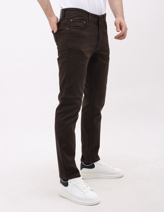 Man met bruine jeans, één hand in de zak. Staand met één been voor het andere.