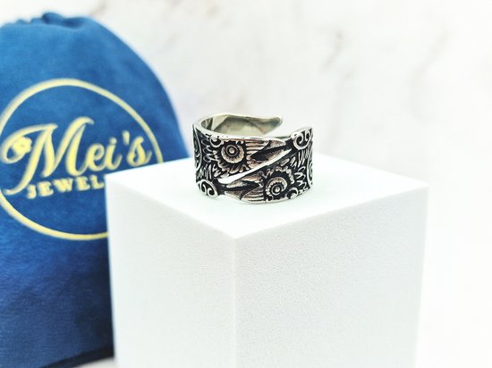 Zilverkleurige ring met Viking Raven patroon, op een witte kubus, met blauw zakje.