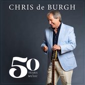 Chris de Burgh in lichtblauwe blazer, staand met gitaar. "50 Years of Music"