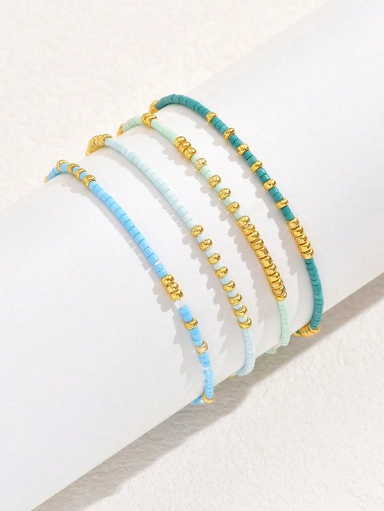 Vier armbandjes met lichtblauwe, turquoise, lichtgroene en gouden kraaltjes.