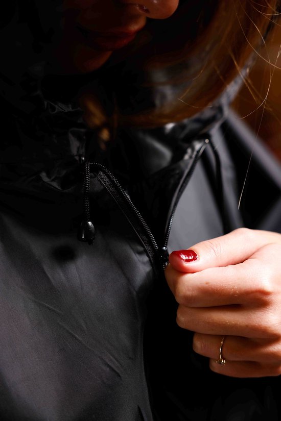 Close-up van een hand met rode nagellak, sluit een rits van een poncho.