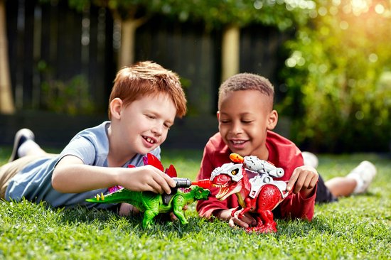 Twee jongens spelen buiten met een groene Stegosaurus en een rode Tyrannosaurus Rex speelgoed dinosaurus.