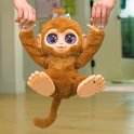 Kind houdt een bruine FurReal Peanut aap omhoog aan de handen.