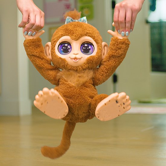 Kind houdt een bruine FurReal Peanut aap omhoog aan de handen.