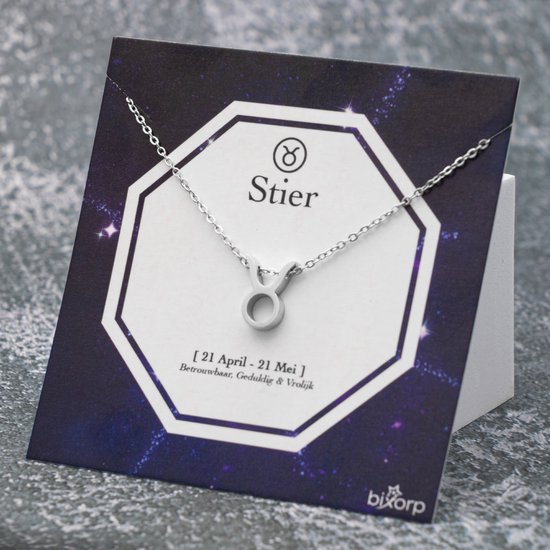 Zilverkleurige ketting met Taurus (Stier) symbool hanger, op een kaart met sterren en tekst.