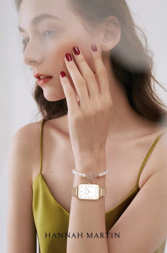 Mannequin portant une montre dorée rectangulaire avec cadran blanc et bracelet en maille, bracelet de perles.