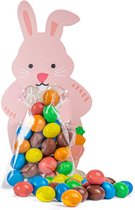 Roze kartonnen konijn met zakje snoepjes en snoepjes ernaast.