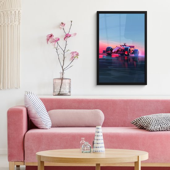 Une voiture de Formule 1 rouge sur une route mouillée au coucher du soleil, se reflétant dans l'eau, accrochée à un mur au-dessus d'un canapé rose.