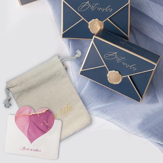 Een stoffen zakje, een wenskaart met een roze hart en twee donkerblauwe geschenkdoosjes met gouden tekst 'Best wishes'.