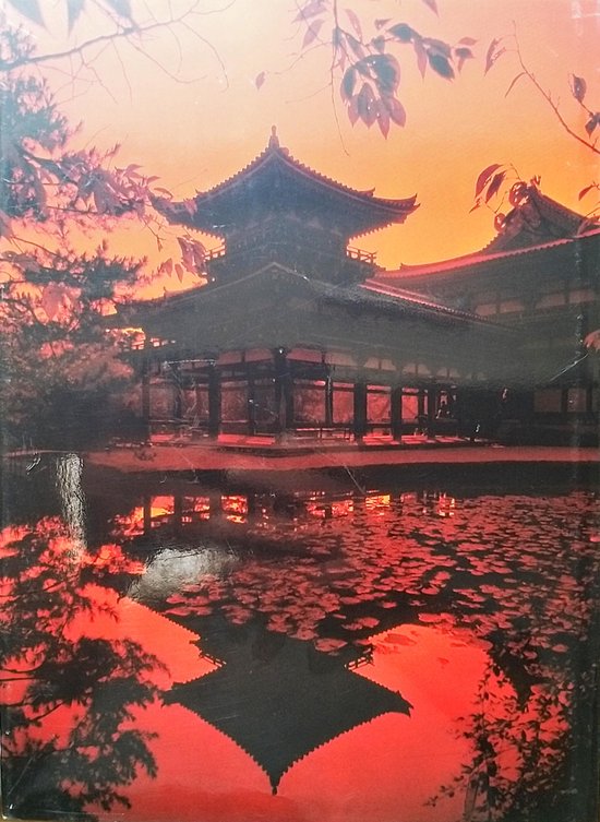 Japanse tempelarchitectuur in oranje schemering, met reflectie in het water.