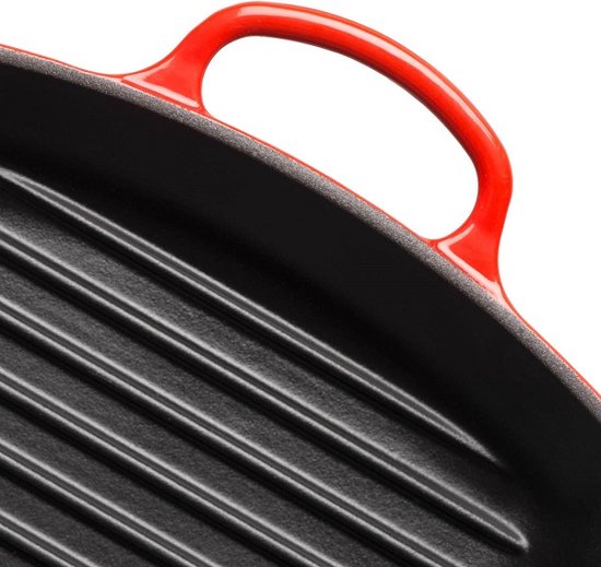 Detail van de rode handgreep en de zwarte ribbels van een grillpan.