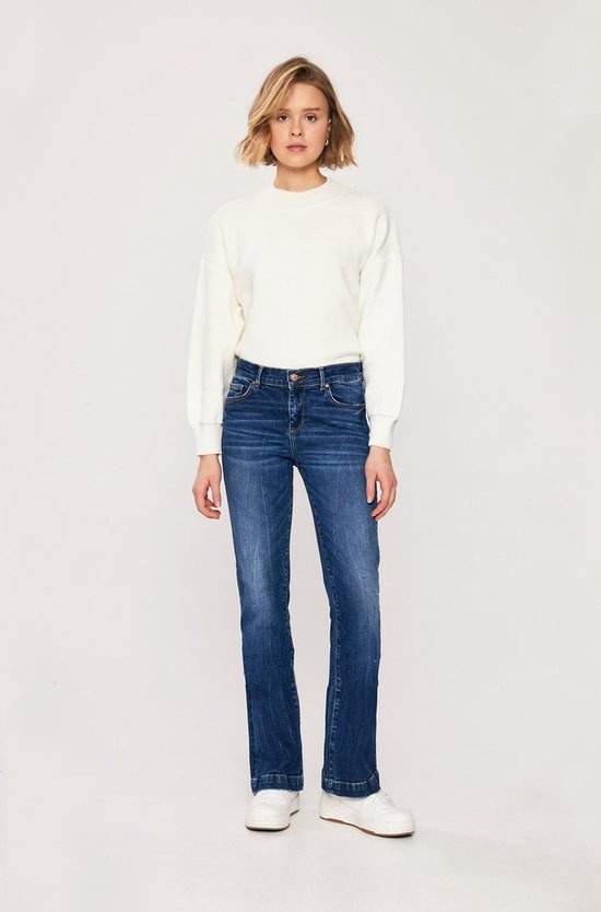 Model in een donkerblauwe flared jeans met een hoge taille, subtiele wassingen en een rechte pijp die naar beneden uitloopt.