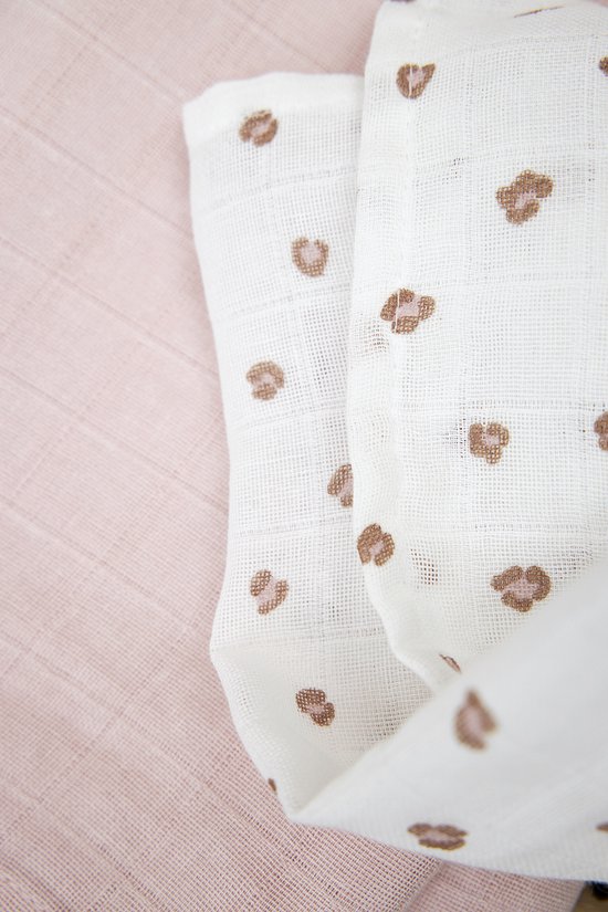 Witte hydrofiele luier met bruine panterprint liggend op een zachtroze luier.