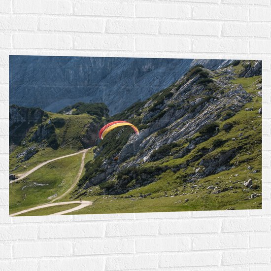 WallClassics - Muursticker - Paraglidend door de Bergen en Natuur - 105x70 cm Foto op Muursticker
