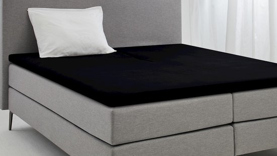 Zwart split hoeslaken op een bed met grijze hoofdbord.