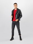 Model in een rode trui, zwart leren jack en donkergrijze jeans met regular fit, omgeslagen broekspijpen en zwarte laarzen.