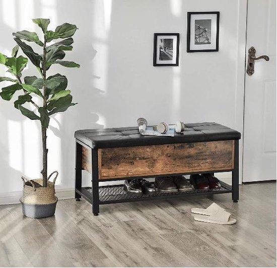 Zwart, leren opbergbank met houtfineer en schoenen op het rek, naast een plant.