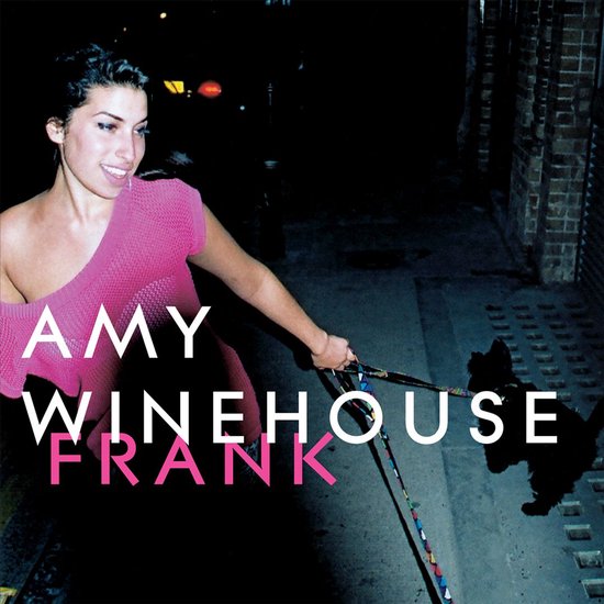 Amy Winehouse, lopend met hond, met een felroze trui, albumtitel 'Frank'.