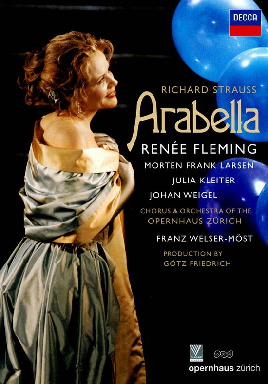 Een vrouw met opgestoken bruin haar draagt een blauw-grijze jurk met gouden accenten. Richard Strauss Arabella, Renée Fleming.
