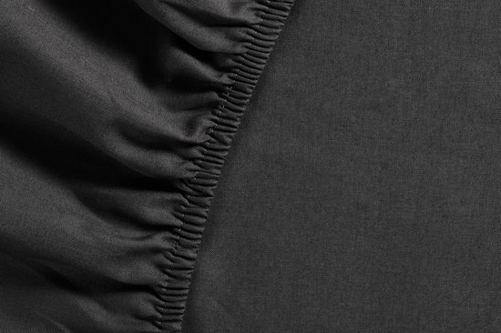 Detail van de elastische rand van een donkergrijs hoeslaken.