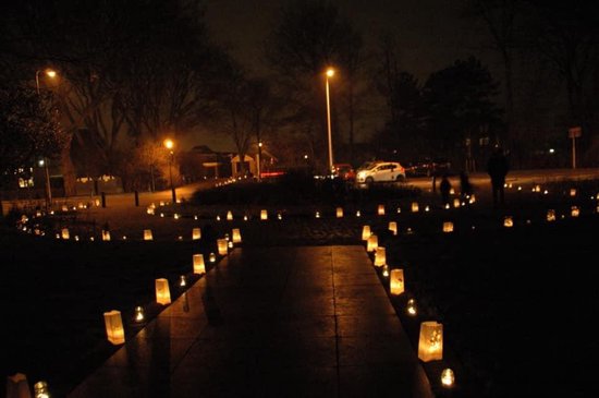 Weg verlicht met waxinelichtjes naar een huis met verlichting.