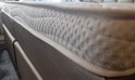 Wit matras met stippenpatroon op de zijwand, bovenop een grijze boxspring.