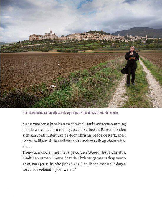 Antoine Bodar, in een zwarte jas, loopt over een pad in Umbrië met Assisi op de heuvels op de achtergrond. Opgenomen tijdens de opnamen voor de RKK-televisieserie.