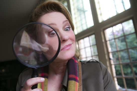 Een vrouw met een sjaal kijkt verrast door een vergrootglas.