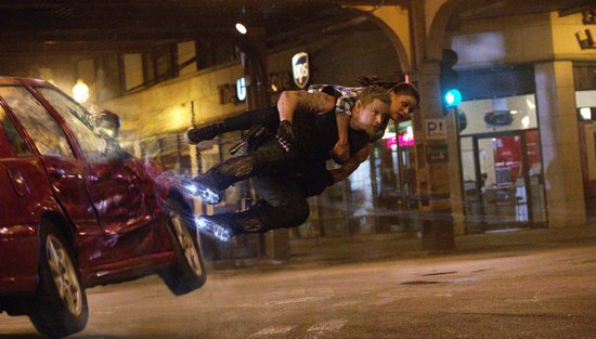 Channing Tatum draagt Mila Kunis tijdens een achtervolging door de stad, met een auto die door de lucht vliegt.