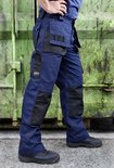 Marineblauwe werkbroek met zwarte accenten op de zakken en knieën, gedragen door een model.